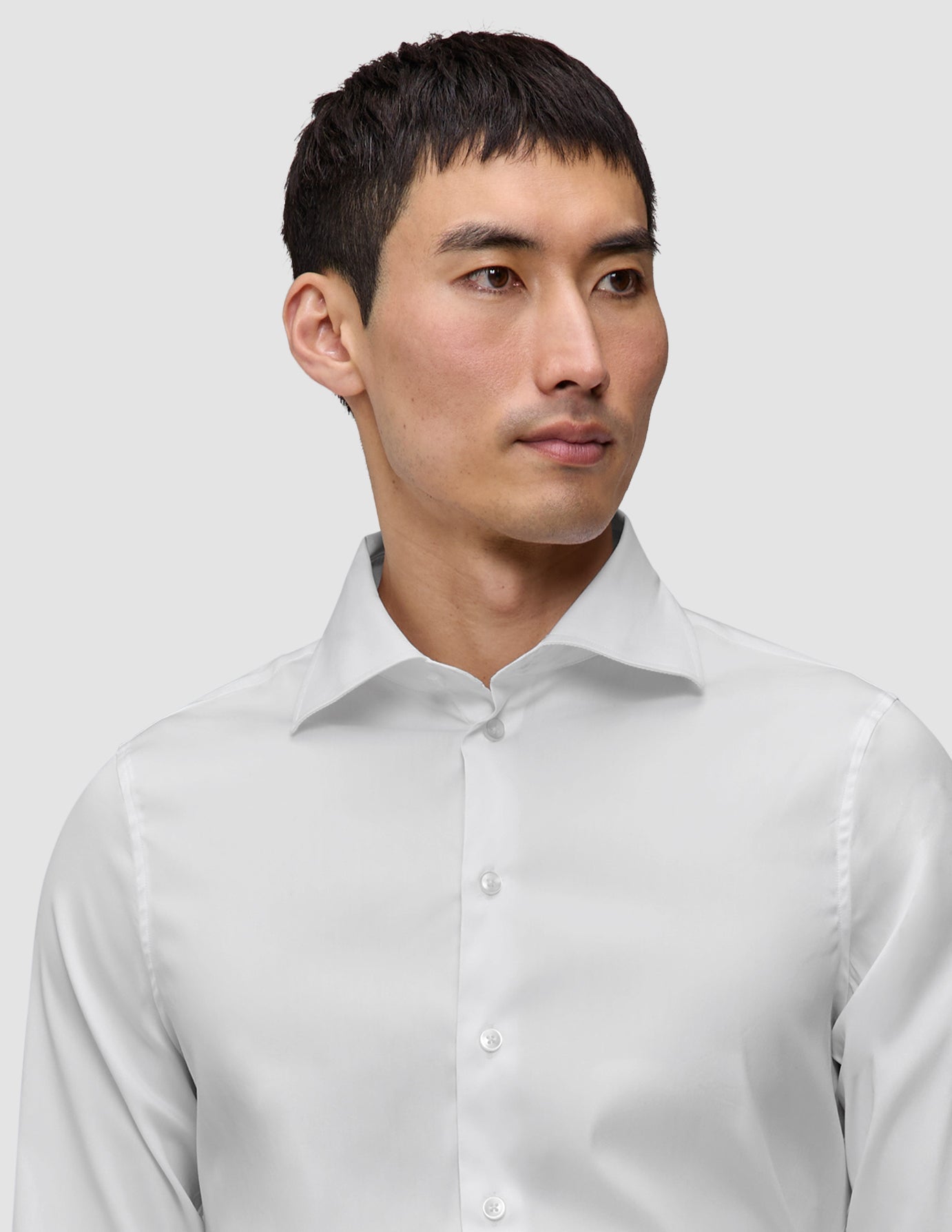 Eine Person, die ein Elevated Shirt White Slim trägt, ein knackig sitzendes, schmal geschnittenes weißes Hemd aus Pima-Baumwolle mit einem Spread-Kragen.